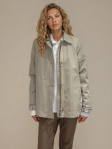 Blouson zippé beige 100% polyester, longueur veste. Coupe droite, emmanchures raglan avec patte de boutonnage de 4 boutons. 2 poches italiennes et 1 poche poitrine intérieure, finitions gansées sur les manches et poches. Doublure tie and dy sur le corps et écossaise sur les manches. Vue face.