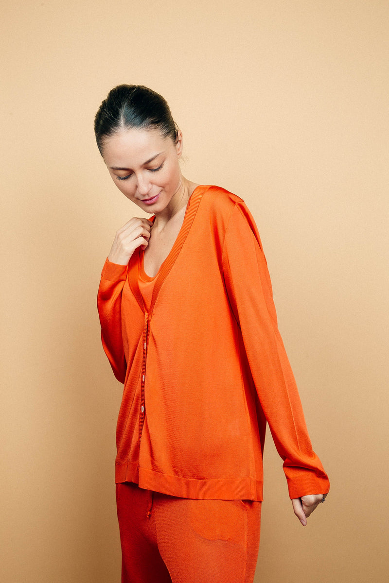 Cardigan orange uni très lumineux en viscose, manches longues, encolure V, 6 boutons, finitions bords côtes. Coupe droite, fluide, peut se porter en twin set avec le débardeur sans manches en viscose orange et le pantalon en viscose orange.