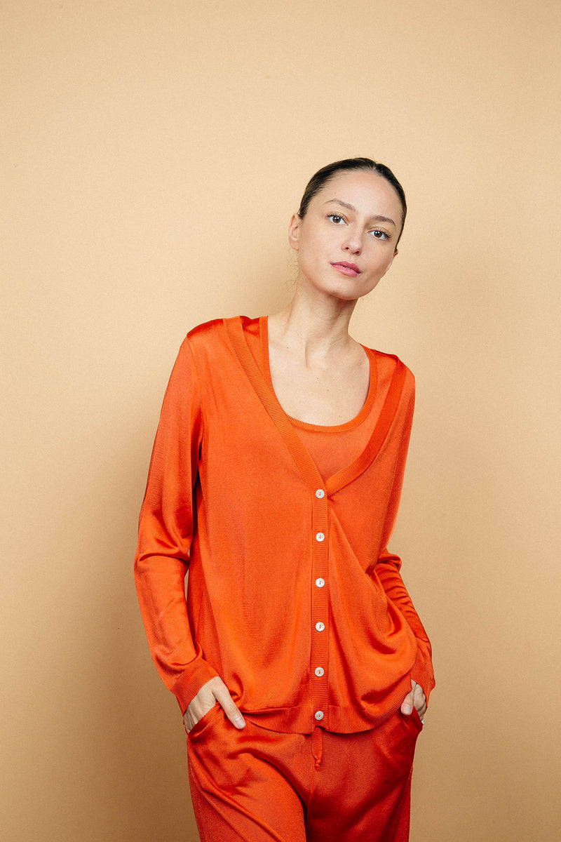 Cardigan orange uni très lumineux en viscose, manches longues, encolure V, 6 boutons, finitions bords côtes. Coupe droite, fluide, peut se porter en twin set avec le débardeur sans manches orange en viscose et le pantalon fluide en viscose orange.