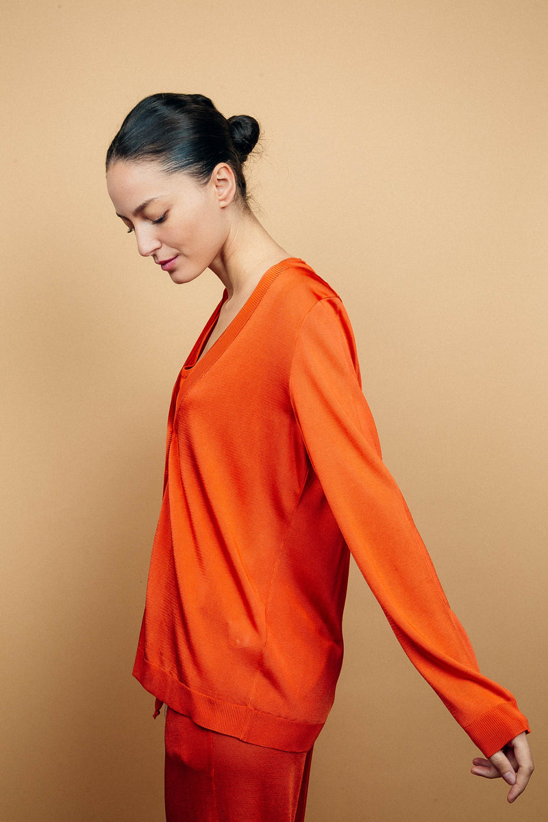 Cardigan orange uni très lumineux en viscose, manches longues, encolure V, 6 boutons, finitions bords côtes. Coupe droite, fluide, peut se porter en twin set avec le débardeur sans manches orange en viscose et le pantalon en viscose fluide orange.