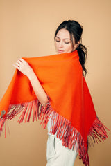 Châle TESSA orange 100% cachemire, forme triangulaire, orné de franges de 14 cm en cuir d'agneau plongé orange. En mouvement pointe Dimensions: 210cm x 80cm.