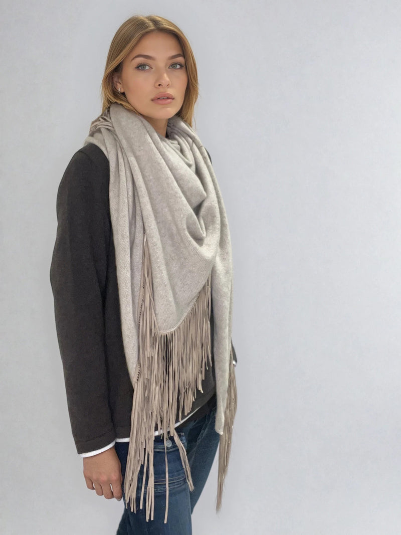 Châle triangulaire 170cm x 80cm coloris beige 100% cachemire orné de franges en cuir d'agneau coloris beige très souple. Le châle est porté sur la photo façon chèche. Vue profil.