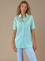 Chemise été femme, coloris vert clair, manches courtes avec un imprimé strié.  La coupe avec un col est droite, les manches courtes arrivent au-dessus du coude. L'imprimé strié mélange des nuances de vert et de jaune. Chemise en 100%viscose, lumineuse, fluide, très douce.
Vue face.