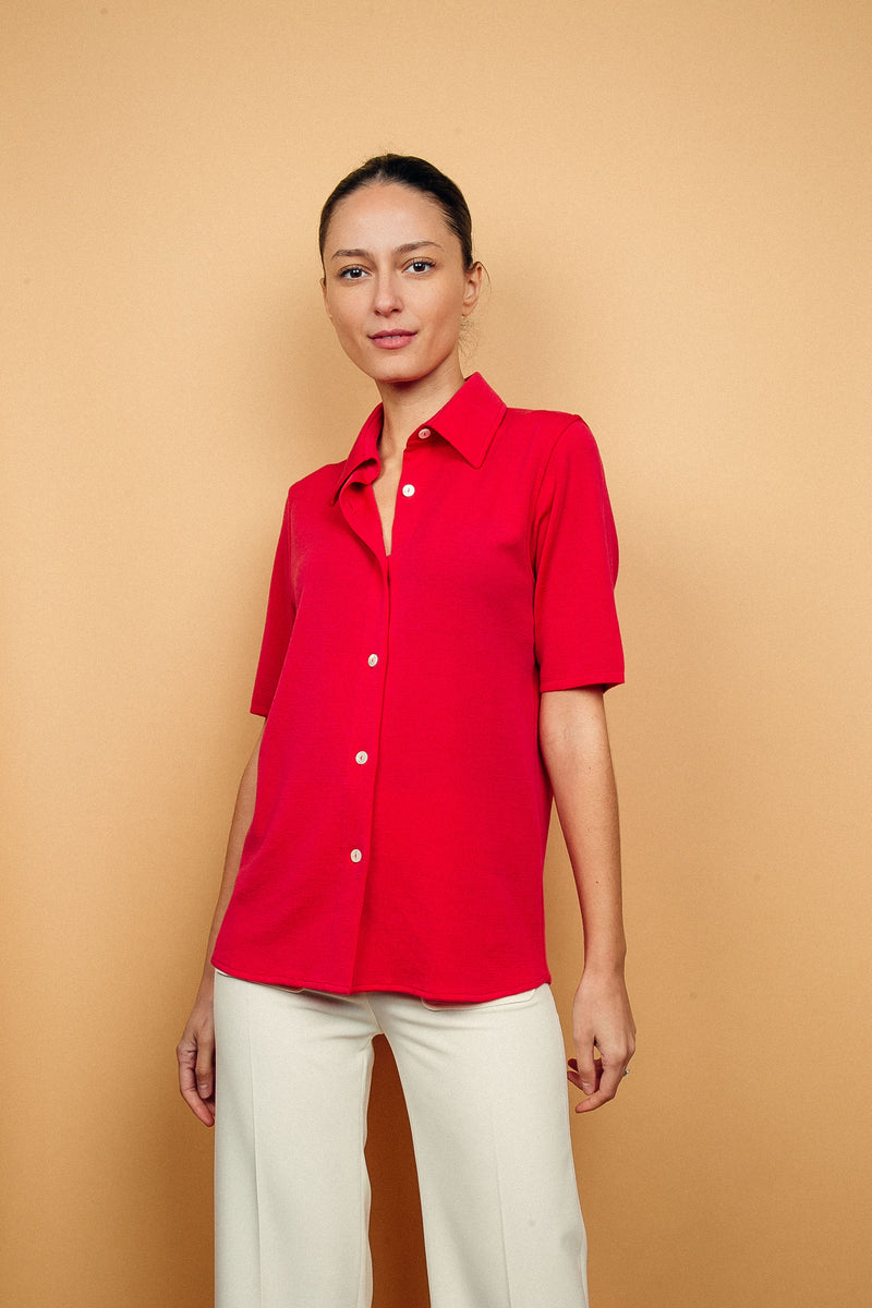 Chemise rose fushia en 100% mérinos, manches courtes couvrant l'avant-bras, coupe droite, hauteur couvrant le bas du dos, col et boutonnage façon chemise. 