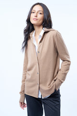 Chemise camel, manches longues, coupe droite, 100% cachemire  avec un col large et des poignets. Chemise portée en superposition sur un chemisier. Vue face.