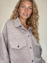 Surchemise coloris taupe fermée par 6 pressions. 2 poches plaquées au niveau de la poitrine et 2 fausses poches côtés.
Se porte comme une veste. Composition: 71%cachemire, 19% soie, 10% polyester, matière très douce. Vue poches.