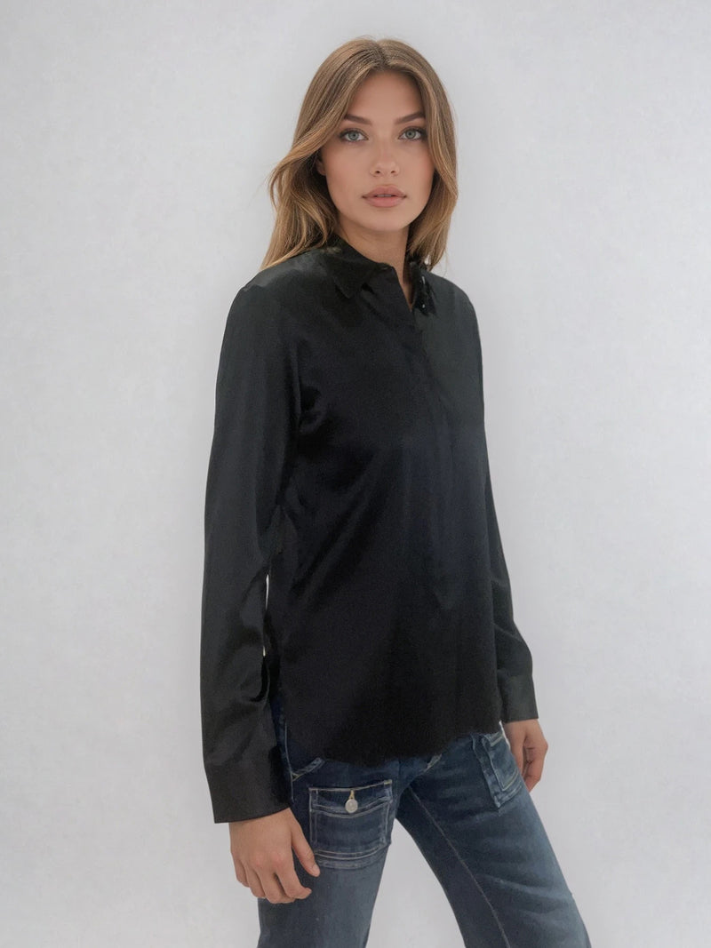 Chemise manches longues coloris noir en soie. Coupe légèrement cintrée avec 2 pinces dans le dos. Patte de boutonnage recouverte.  Vue profil.