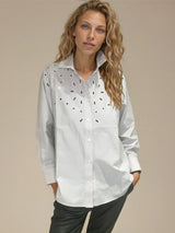 Chemise manches longues en 100% coton rayé beige et blanc. Petit col et forme trapèze avec des broderies ajourées au niveau du buste. Vue face.