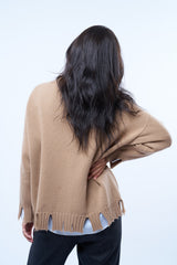 Gilet manches longues coloris camel avec une coupe oversize. Sur le long de l'encolure côté gauche : bande  de couleur grise. Le gilet présente des détails déchirés irréguliers aux bas des manches et sur tout le pourtour du bas . Emmanchures basses. Composition: 42%cachemire, 8% soie, 50%mérinos. Vue dos.