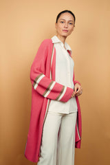 Gilet long rose malabar tricoté au point mousse. Coupe confort, 80% de coton et 15% de cachemire. Les emmanchures sont basses, la manche est large, pas resserrée et a 3 bandes rayées espacées, chacune étant composée d'une ligne écru collée à une ligne taupe. Bande également présente sur tout le pourtour du gilet et sur les fentes de chaque côté.