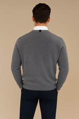 Gilet col V gris pour homme en cachemire, soie, mérinos. La coupe est droite, il est boutonné devant. Sur la nuque se trouve un petit carré écru et noir très discret. Emmanchures droites, allure décontractée. Vue dos.