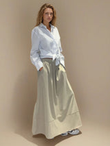 Jupe longue beige en 100% coton, la coupe est ample et se termine par une finition ballon. Taille élastiquée avec 2 poches italiennes sur les côtés.
Vue profil.