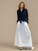 Jupe longue blanche en 100% coton, la coupe est ample et se termine par une finition ballon. Taille élastiquée avec 2 poches italiennes sur les côtés.
Vue face.