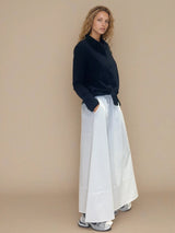 Jupe longue blanche en 100% coton, la coupe est ample et se termine par une finition ballon. Taille élastiquée avec 2 poches italiennes sur les côtés.
Vue profil.