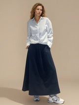 Jupe longue marine en 100% coton, la coupe est ample et se termine par une finition ballon. Taille élastiquée avec 2 poches italiennes sur les côtés.
Vue face.