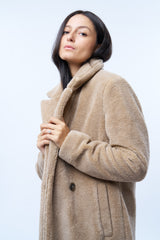 Manteau beige en fausse fourrure effet bouclé. 100%polyester. Coupe droite façon pardessus croisé, fermé par 2 boutons. Col tailleur, 2 poches cotés. Détail encolure.