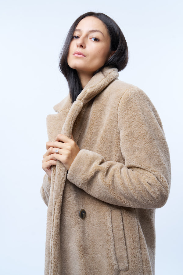 Manteau beige en fausse fourrure effet bouclé. 100%polyester. Coupe droite façon pardessus croisé, fermé par 2 boutons. Col tailleur, 2 poches cotés. Détail encolure.