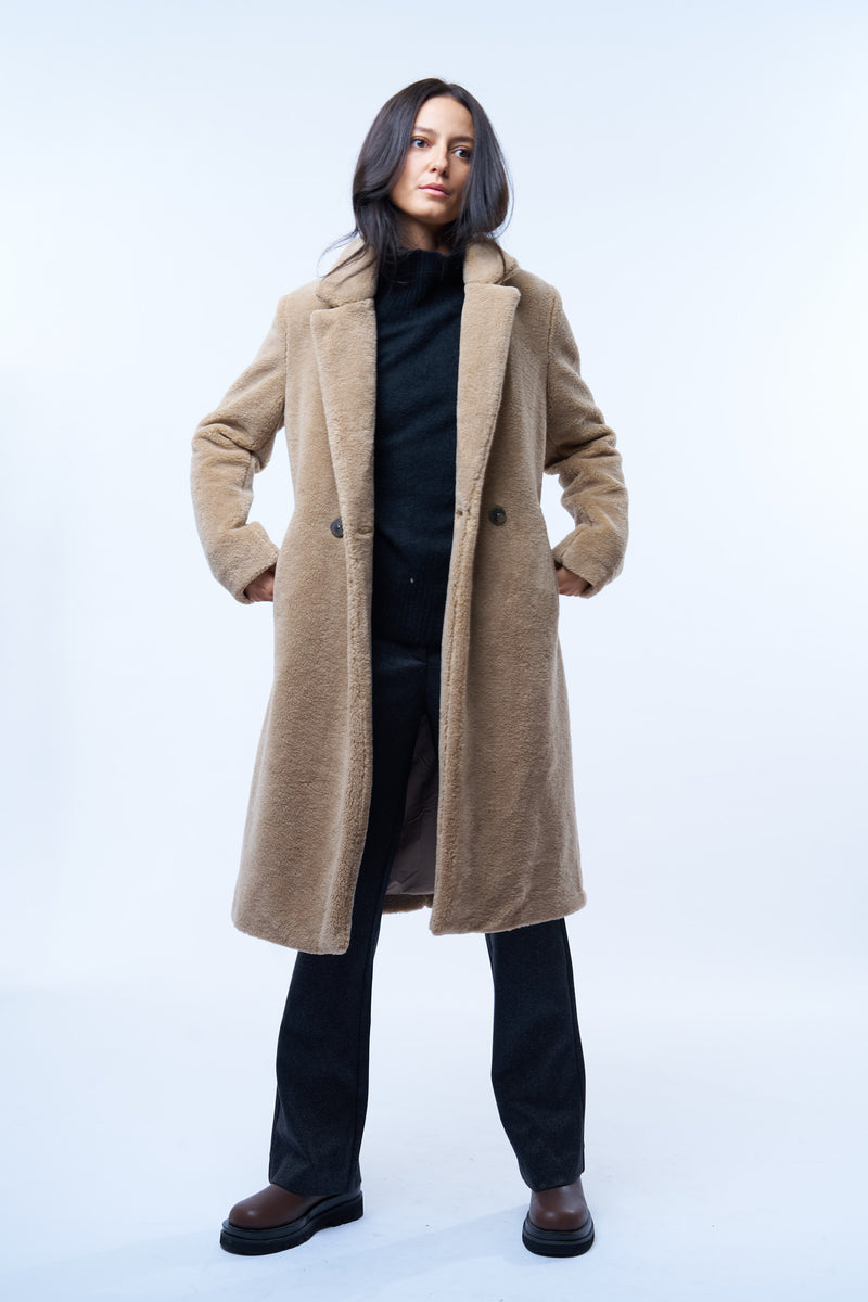 Manteau beige en fausse fourrure effet bouclé. 100%polyester. Coupe droite façon pardessus croisé, fermé par 2 boutons. Col tailleur, 2 poches cotés.