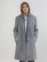 Manteau coupe droite style pardessus masculin coloris gris très clair fermé par 3 boutons. Manches montées, 2 poches. Un col façon doudoune se zippe sur le col tailleur.