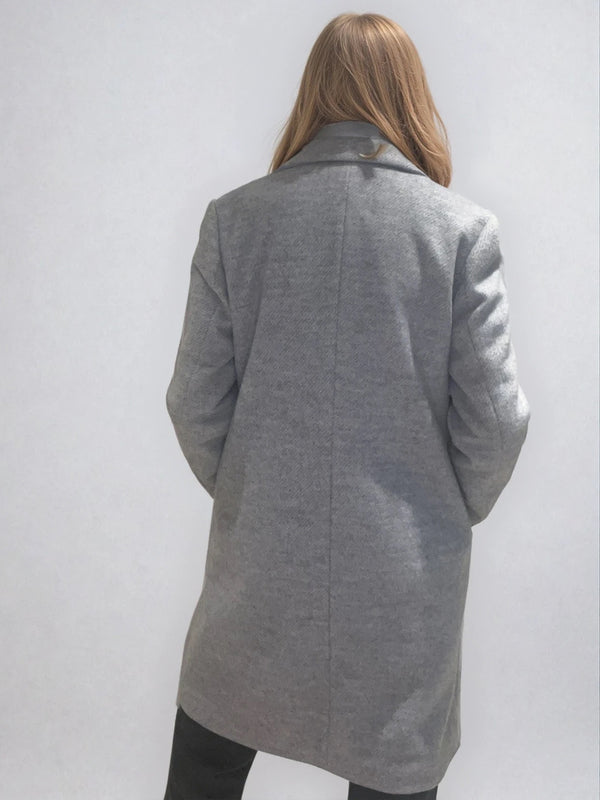 Manteau coupe droite style pardessus masculin coloris gris très clair fermé par 3 boutons. Manches montées, 2 poches. Un col façon doudoune se zippe sur le col tailleur.