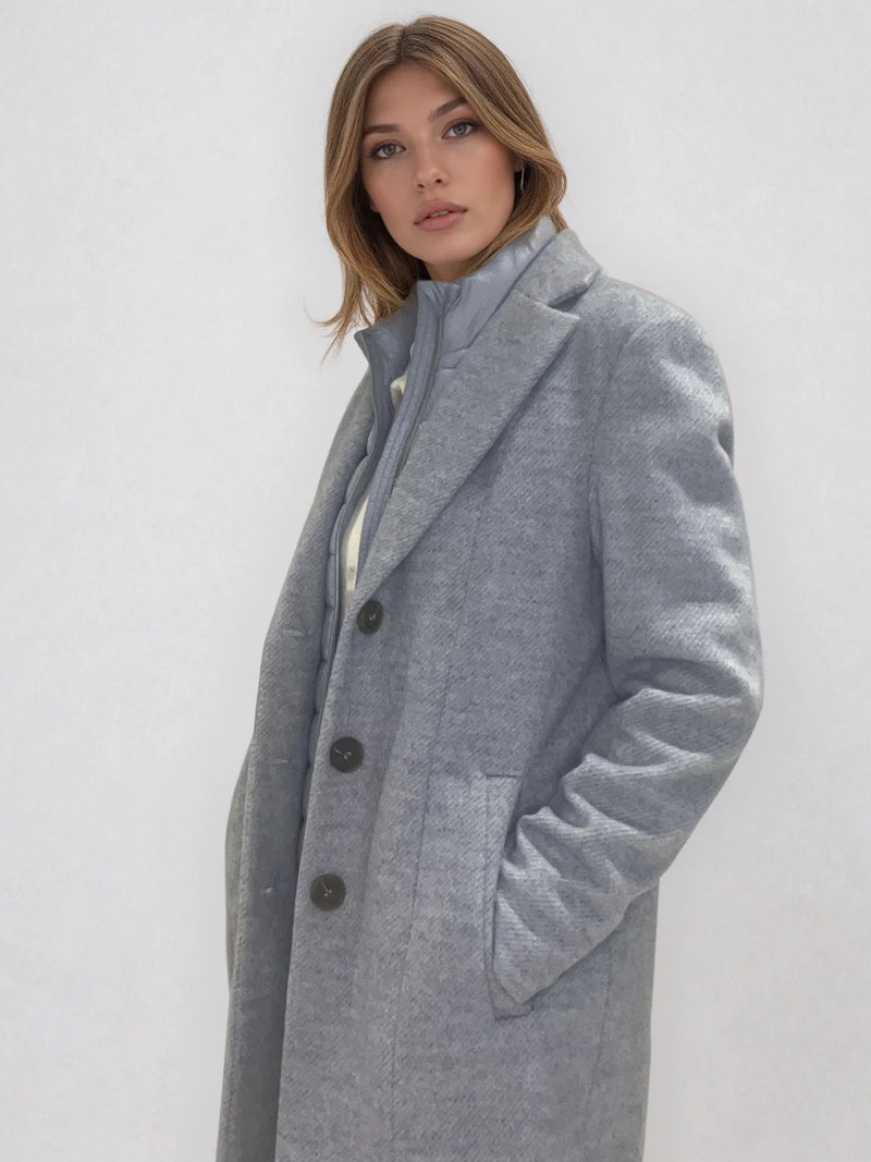 Manteau coupe droite style pardessus masculin coloris gris très clair fermé par 3 boutons. Manches montées, 2 poches. Un col façon doudoune se zippe sur le col tailleur.