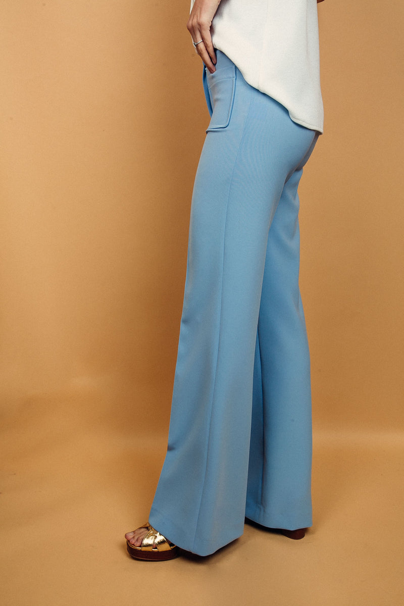 Pantalon BRIGITTE ciel, coupe large sur toute la jambe, 2 poches plaquées sur le devant. Taille placée avec bouton doré. Texture douce et fluide 95% viscose et 5% élasthanne. Vue profil.