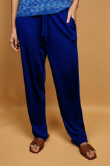Pantalon bleu uni très lumineux, la taille est élastiquée ajustée par un lacet en viscose, il a 1 poche de chaque côté.  La forme est droite, le bas n'est pas resserré. Il est en 100% viscose ce qui  apporte au pantalon de la fluidité, de la brillance et un confort maxi.