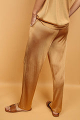 Pantalon doré miel uni très lumineux, la taille est élastiquée ajustée par un lacet en viscose, il a 1 poche de chaque côté.  La forme est droite, le bas n'est pas resserré. Il est en 100% viscose ce qui apporte au pantalon de la fluidité, de la brillance et un confort maxi. Vue dos.