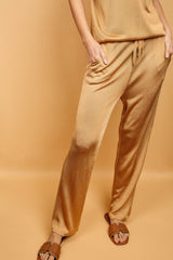 Pantalon doré miel uni très lumineux, la taille est élastiquée ajustée par un lacet en viscose, il a 1 poche de chaque côté.  La forme est droite, le bas n'est pas resserré. Il est en 100% viscose ce qui apporte au pantalon de la fluidité, de la brillance et un confort maxi.
