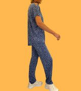 Pantalon imprimé bleu très lumineux: mélange de nuances de bleu, de violet, de blanc réunis dans un graphisme strié. La taille est élastique est ajustée par un lacet en viscose, il a 1 poche de chaque côté.  La forme est droite, le bas n'est pas resserré. Il est en 100% viscose ce qui apporte au pantalon de la fluidité, de la brillance et un confort maxi.  Associé au top en viscose imprimé bleu avec épaules dénudées. Vue profil.