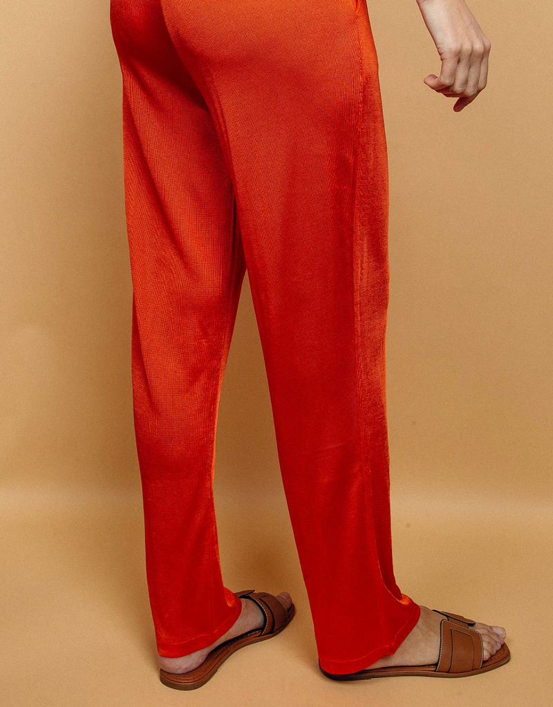 Pantalon orange uni très lumineux, la taille est élastiquée ajustée par un lacet en viscose, il a 1 poche de chaque côté.  La forme est droite, le bas n'est pas resserré. Il est en 100% viscose ce qui apporte au pantalon de la fluidité, de la brillance et un confort maxi.