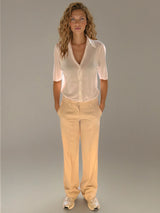 Pantalon pour femme coloris beige, fluide et léger composé de 97%polyester et de 3% élasthanne. Coupe droite, poches italiennes. Ceinture avec passants, bouton doré.
Vue face.