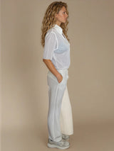Pantalon pour femme coloris blanc, fluide et léger composé de 94%polyester et de 6% élasthanne. Coupe droite, poches italiennes. Ceinture avec passants, bouton doré.
Vue profil.