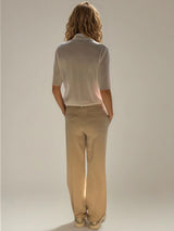 Pantalon pour femme coloris beige, fluide et léger composé de 97%polyester et de 3% élasthanne. Coupe droite, poches italiennes. Ceinture avec passants, bouton doré,
 2 fausses poches passepoilés .
Vue dos.