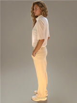Pantalon pour femme coloris beige, fluide et léger composé de 97%polyester et de 3% élasthanne. Coupe droite, poches italiennes. Ceinture avec passants, bouton doré,
 2 fausses poches passepoilés .
Vue profil.