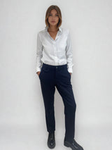 Pantalon marine de ville avec une forme droite. Poches italiennes et dos élastiqué. Détail de la patte rehaussée de fil lurex au niveau des passants. Vue face.