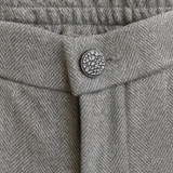 Pantalon droit gris avec un motif chevrons fines rayures. La taille dans le dos est élastiquée. Vue du bouton strass.