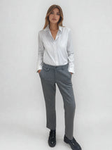 Pantalon droit gris avec un motif chevrons fines rayures. La taille dans le dos est élastiquée. Poches italiennes, patte au niveau d'un passant rehaussée d'un fil lurex. Vue face.