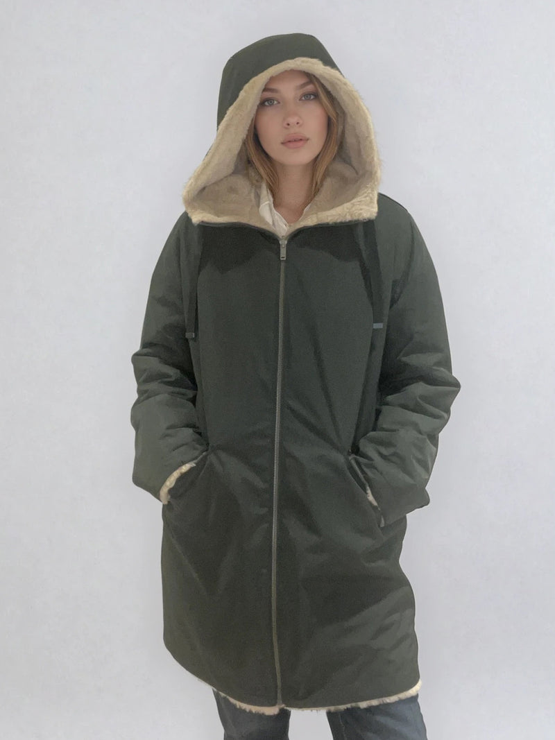 Parka kaki avec capuche doublée en 100% polyester réversible avec d'un côté une face déperlante marine et de l'autre une face façon fausse fourrure beige. Elle se ferme par un zip, a 2 poches zippées côté déperlant . Le bas des manches se retournent,  elle a une coupe droite et arrive à mi-cuisses. Vue face.
