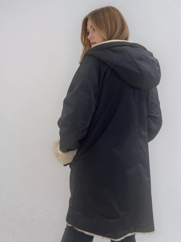 Parka marine avec capuche doublée en 100% polyester réversible avec d'un côté une face déperlante marine et de l'autre une face façon fausse fourrure beige. Elle se ferme par un zip, a 2 poches zippées côté déperlant . Le bas des manches se retournent,  elle a une coupe droite et arrive à mi-cuisses. Vue dos.