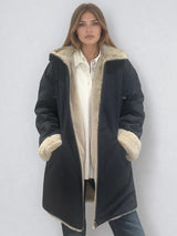 Parka marine avec capuche doublée en 100% polyester réversible avec d'un côté une face déperlante marine et de l'autre une face façon fausse fourrure beige. Elle se ferme par un zip, a 2 poches zippées côté déperlant . Le bas des manches se retournent,  elle a une coupe droite et arrive à mi-cuisses. Vue face.