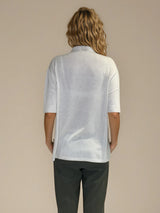 Polo femme d'été coloris beige en 83% viscose et 17% nylon: fluide, coupe large et longue fendue sur les côtés. Le polo a un petit col qui s'ouvre sur 3 boutons, les manches courtes couvrent les avant-bras. Vue dos.