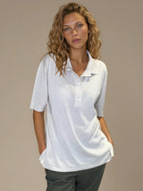 Polo femme d'été coloris beige en 83% viscose et 17% nylon: fluide, coupe large et longue fendue sur les côtés. Le polo a un petit col qui s'ouvre sur 3 boutons, les manches courtes couvrent les avant-bras. Vue face.