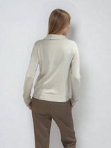 Polo manches longues coloris beige. La coupe est légèrement ajustée et féminine. 
Le polo est en 100% tencel, fibre respirante artificielle et écologique provenant de la cellulose du bois. Vue dos.