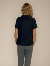 Polo femme manches courtes coloris noir. Le polo est en 100% polyester, il a une maille texturée en nid d'abeille. Petit col. Forme droite, maille légère et aérienne.
Vue dos.