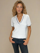 Polo coloris blanc pour femme avec manches courtes, esprit tennis. L' encolure V est rehaussée par une rayure grise, détail présent également sur le bas des manches. Petit col.
100%viscose.
Vue face.