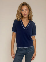 Polo coloris marine pour femme avec manches courtes, esprit tennis. L' encolure V est rehaussée par une rayure grise, détail présent également sur le bas des manches. Petit col.
100%viscose.
Vue face.