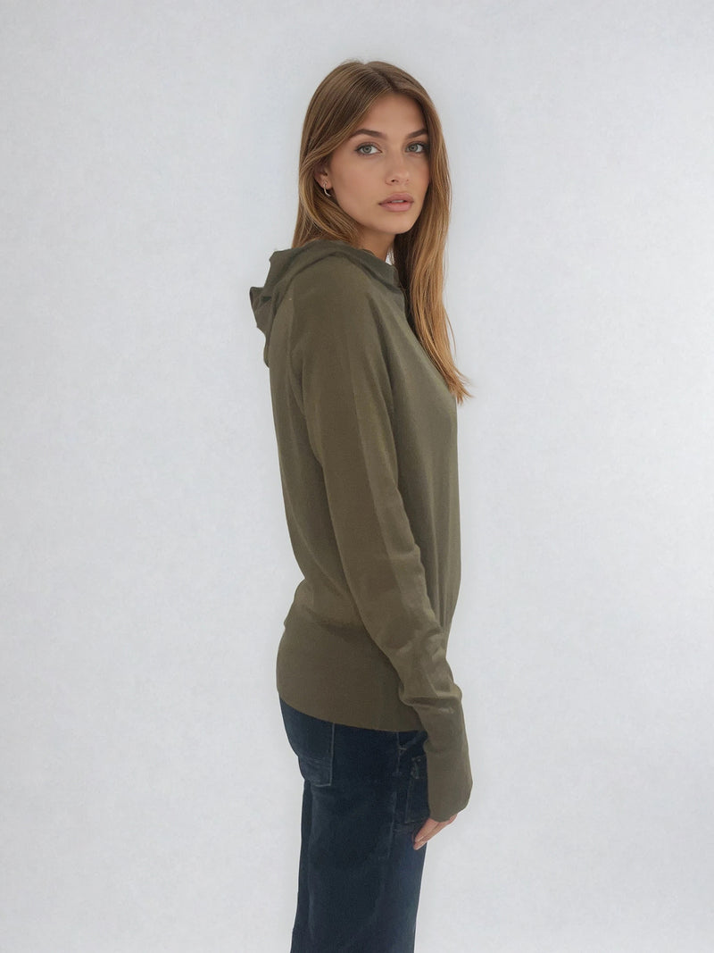 Pull encolure ronde souple avec capuche coloris kaki en 100% laine mérinos. Manches longues terminées par un long poignet côtelé avec une ouverture pour y glisser le pouce comme une mitaine. Emmanchures raglan, large bande côtelée sur le bas. Vue profil.