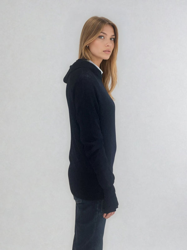 Pull encolure ronde souple avec capuche coloris marine en 100% laine mérinos. Manches longues terminées par un long poignet côtelé avec une ouverture pour y glisser le pouce comme une mitaine. Emmanchures raglan, large bande côtelée sur le bas. Vue profil.