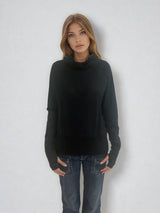 Pull encolure ronde souple avec capuche coloris noir en 100% laine mérinos. Manches longues terminées par un long poignet côtelé avec une ouverture pour y glisser le pouce comme une mitaine. Emmanchures raglan, large bande côtelée sur le bas. Vue face.
